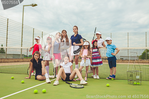 Image of Portrait of group of girls as tennis players holding tennis racket against green grass of outdoor court