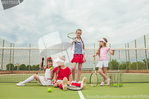 Image of Portrait of group of girls as tennis players holding tennis racket against green grass of outdoor court