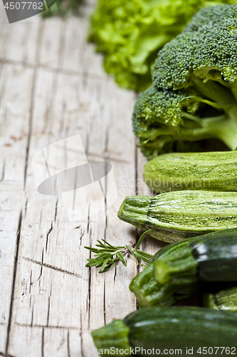 Image of Variety of green organic vegetables on rustic wooden background.