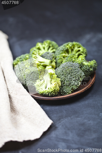 Image of Fresh green organic broccoli in brown plate and linen napkin.