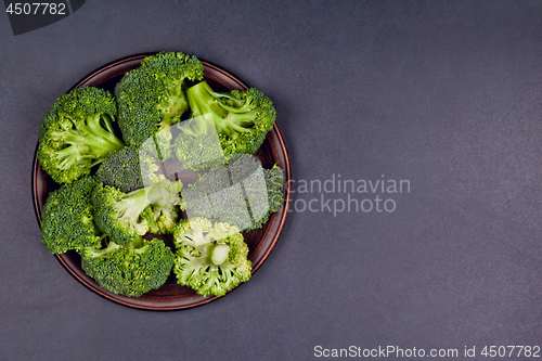 Image of Fresh green organic broccoli in brown plate on black board backg