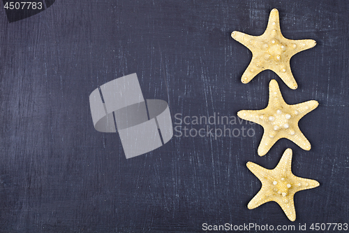 Image of Top view of three starfish on black background.