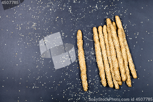 Image of Italian grissini bread sticks with sesame seeds on black board b