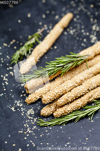 Image of Italian grissini bread sticks with sesame and rosemary herb on b