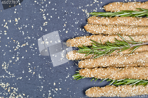 Image of Italian grissini bread sticks with sesame and rosemary herb on b