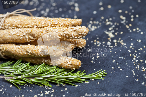 Image of Italian grissini bread sticks with sesame and rosemary herb on b