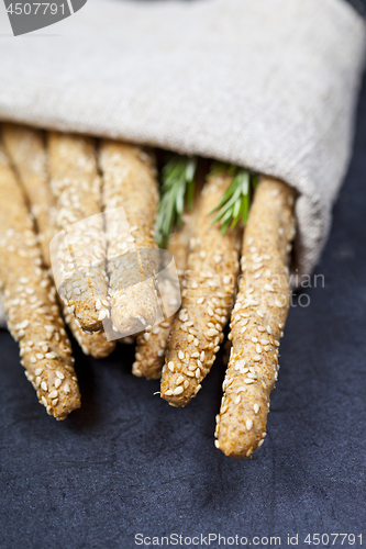 Image of Italian grissini or salted bread sticks with rosemary herb on li