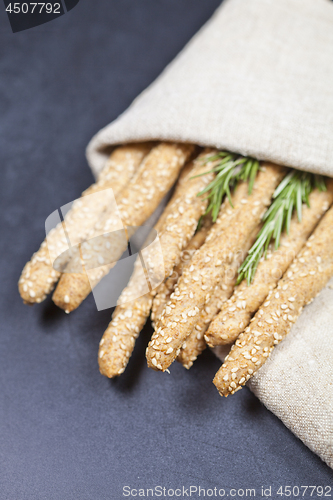 Image of Italian grissini bread sticks with sesame and rosemary herb on b