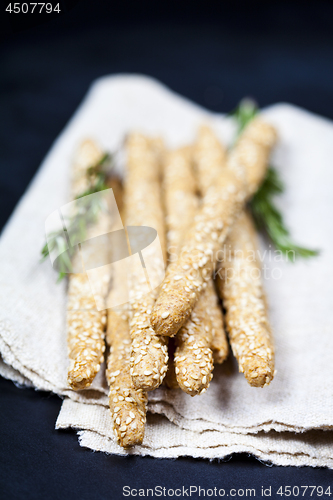 Image of Italian grissini bread sticks with sesame and rosemary herb on b