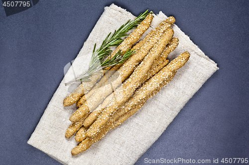 Image of Italian grissini or salted bread sticks with rosemary herb on li