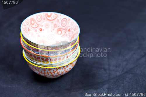 Image of Stack of colorful empty ceramic bowls closeup on black board bac
