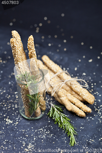 Image of Italian grissini bread sticks with sesame and rosemary herb on b