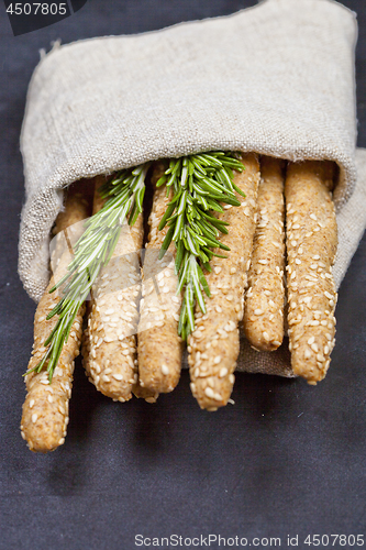 Image of Italian grissini bread sticks with rosemary herb on linen napkin