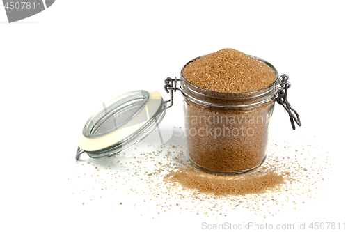 Image of Brown cane sugar in glass jar isolated on white background.