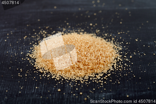 Image of Brown cane sugar heap on black board.