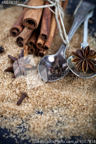 Image of Brown cane sugar, cinnamon sticks and star anise closeup on blac