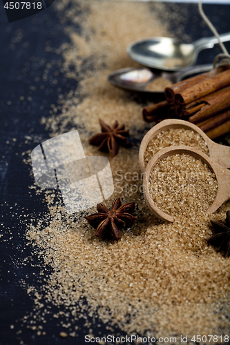 Image of Brown cane sugar, cinnamon sticks and star anise closeup on blac