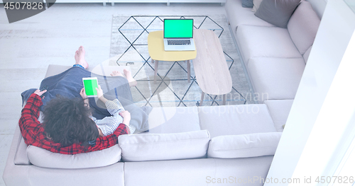 Image of couple relaxing at  home with tablet computers