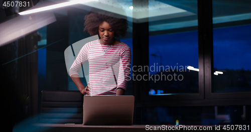 Image of black businesswoman using a laptop in night startup office