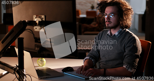 Image of man working on computer in dark office