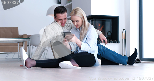 Image of Young Couple using digital tablet on the floor