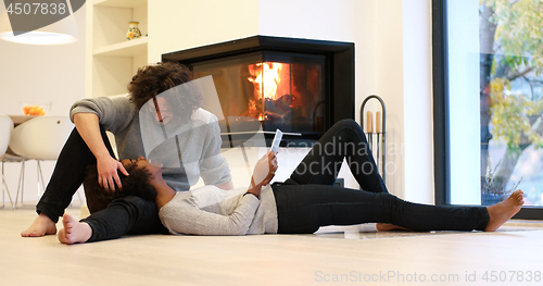 Image of multiethnic couple using tablet computer on the floor