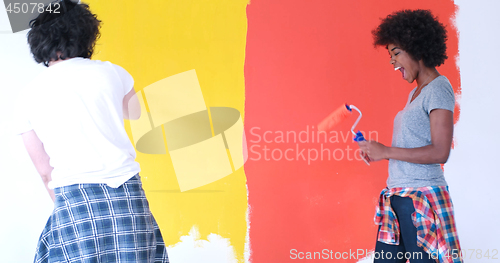 Image of multiethnic couple painting interior wall
