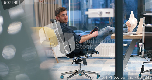 Image of businessman sitting with legs on desk