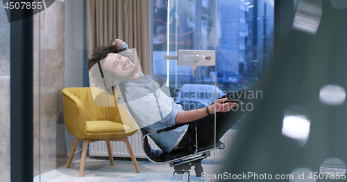 Image of businessman sitting with legs on desk