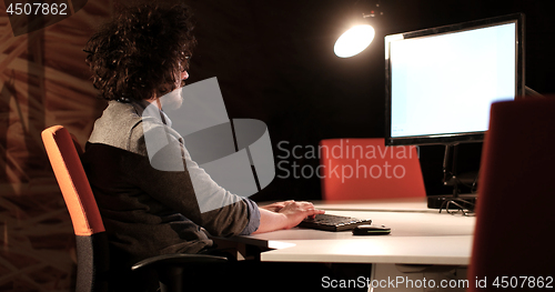 Image of man working on computer in dark office