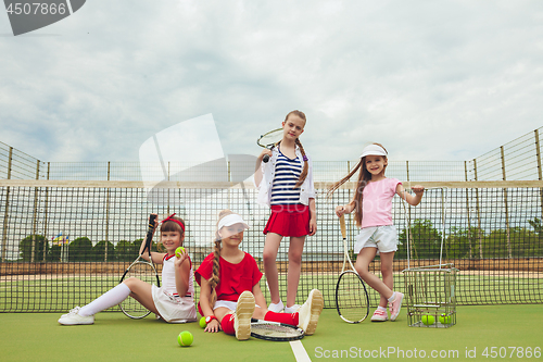 Image of Portrait of group of girls as tennis players holding tennis racket against green grass of outdoor court