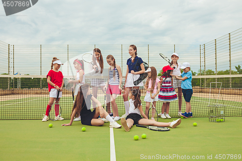 Image of Portrait of group of girls as tennis players holding tennis racket against green grass of outdoor court