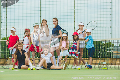 Image of Portrait of group of girls as tennis players holding tennis racket against green grass of outdoor court