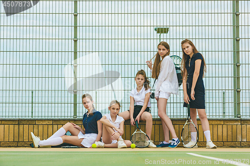 Image of Portrait of group of girls as tennis players holding tennis racket against green grass of outdoor court