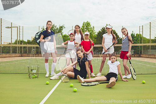 Image of Portrait of group of girls as tennis players holding tennis racket against green grass of outdoor court