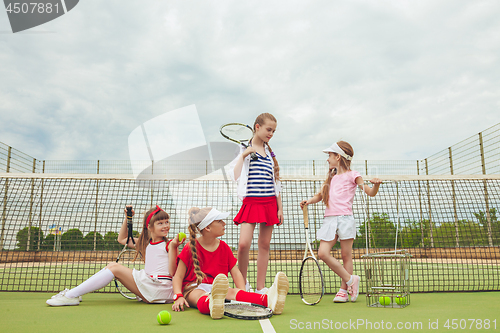 Image of Portrait of group of girls as tennis players holding tennis racket against green grass of outdoor court