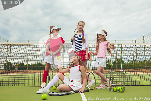 Image of Portrait of group of girls as tennis players holding tennis racket against green grass of outdoor court