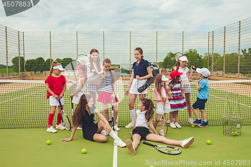 Image of Portrait of group of girls as tennis players holding tennis racket against green grass of outdoor court