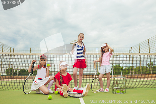 Image of Portrait of group of girls as tennis players holding tennis racket against green grass of outdoor court