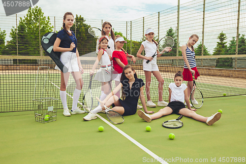 Image of Portrait of group of girls as tennis players holding tennis racket against green grass of outdoor court