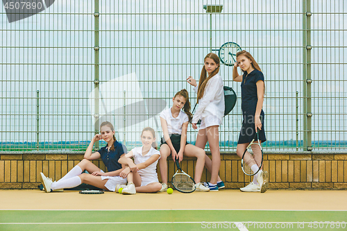 Image of Portrait of group of girls as tennis players holding tennis racket against green grass of outdoor court