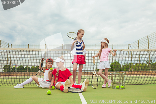 Image of Portrait of group of girls as tennis players holding tennis racket against green grass of outdoor court