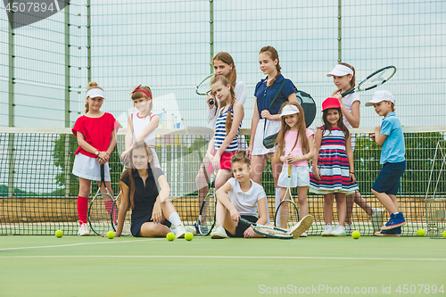 Image of Portrait of group of girls as tennis players holding tennis racket against green grass of outdoor court