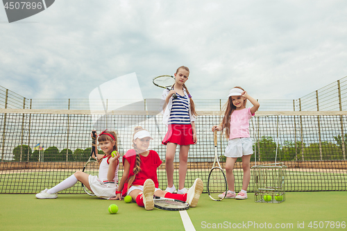 Image of Portrait of group of girls as tennis players holding tennis racket against green grass of outdoor court