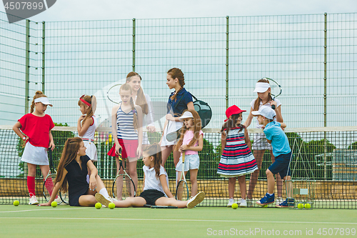 Image of Portrait of group of girls as tennis players holding tennis racket against green grass of outdoor court