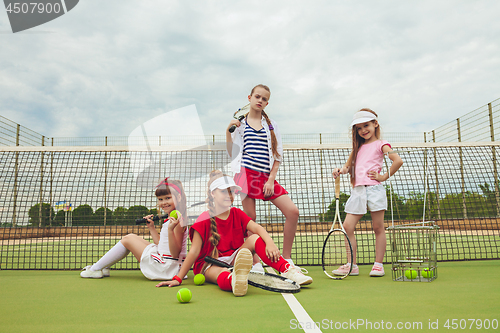 Image of Portrait of group of girls as tennis players holding tennis racket against green grass of outdoor court