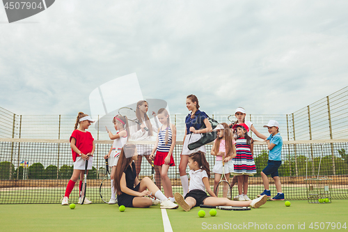 Image of Portrait of group of girls as tennis players holding tennis racket against green grass of outdoor court