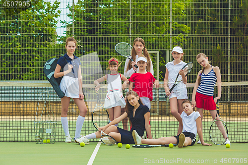 Image of Portrait of group of girls as tennis players holding tennis racket against green grass of outdoor court