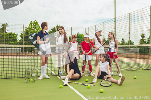 Image of Portrait of group of girls as tennis players holding tennis racket against green grass of outdoor court