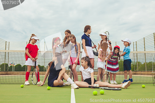 Image of Portrait of group of girls as tennis players holding tennis racket against green grass of outdoor court